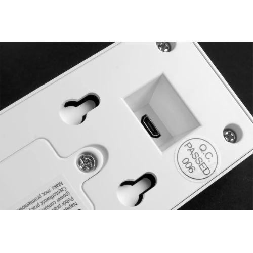 Zdjęcie przedstawia tylną część białego domofonu bezprzewodowego z widocznymi otworami montażowymi i portem micro USB. Na urządzeniu znajduje się naklejka z napisem "Q.C PASSED 006".