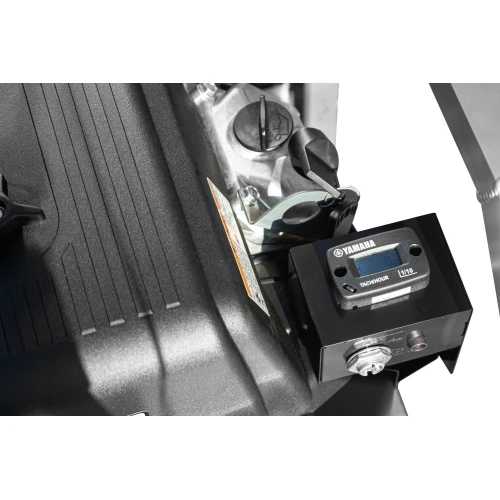 Zbliżenie na część agregatu prądotwórczego z widocznym logo Yamaha i wyświetlaczem tachometru. Obok znajduje się czarna obudowa z teksturą i metalowe elementy konstrukcyjne.