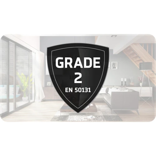 Na zdjęciu znajduje się czarny emblemat w kształcie tarczy z napisem "GRADE 2 EN 50131", umieszczony na tle nowoczesnego wnętrza salonu. Produkt symbolizuje bezprzewodowy system alarmowy, spełniający standardy bezpieczeństwa klasy 2.