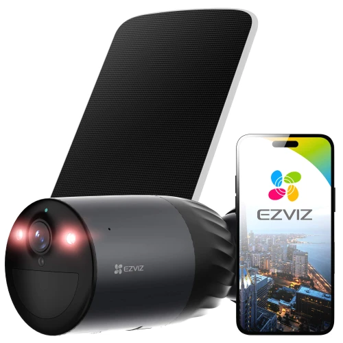 Na zdjęciu znajduje się kamera monitorująca z własnym zasilaniem, obok której widoczny jest smartfon z logo EZVIZ na ekranie. Kamera ma cylindryczny kształt i jest połączona z panelem słonecznym.