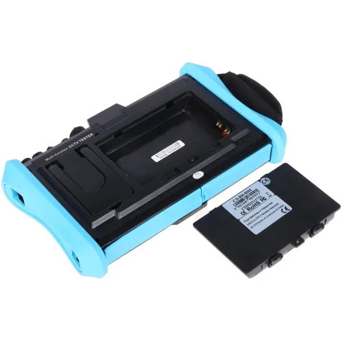 Na zdjęciu znajduje się czarno-niebieskie urządzenie z otwartą komorą na akumulator, obok którego leży wyjęty akumulator. Urządzenie ma ergonomiczny kształt z uchwytami po bokach i jest przeznaczone do testowania systemów CCTV.