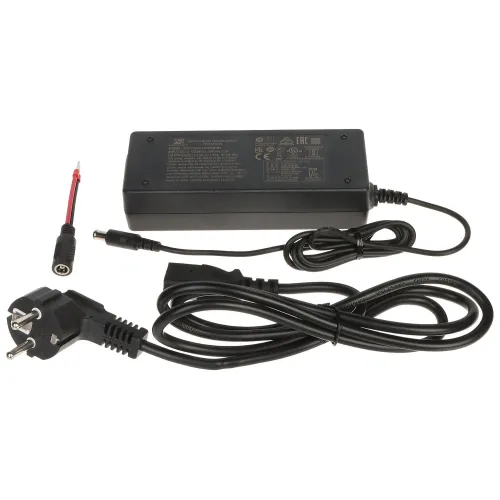 Na zdjęciu znajduje się czarny zasilacz sieciowy z dołączonym kablem zasilającym oraz dodatkowym przewodem z wtykiem. Zasilacz posiada etykietę z informacjami technicznymi i certyfikatami.