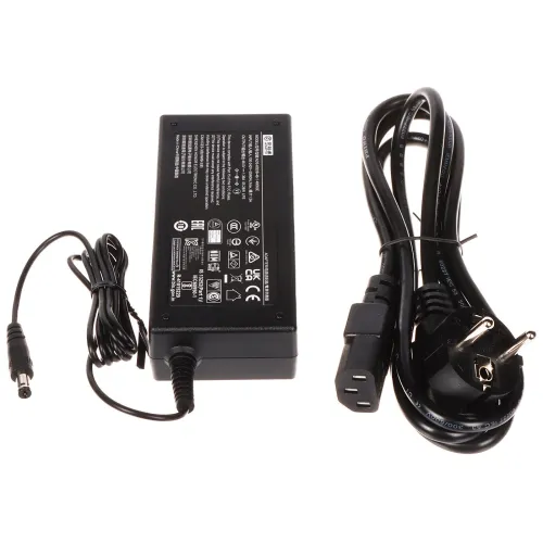 Na zdjęciu znajduje się zasilacz sieciowy z przewodem oraz osobny kabel zasilający z wtyczką. Zasilacz ma czarną obudowę z białymi oznaczeniami technicznymi na górnej powierzchni.