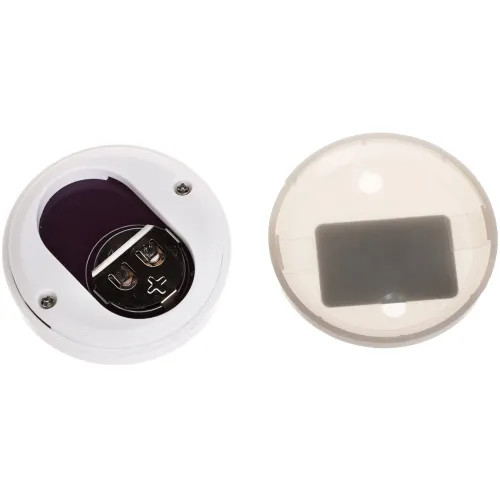 Na zdjęciu znajdują się dwa okrągłe urządzenia elektroniczne, jedno z widocznym miejscem na baterię i śrubkami, a drugie z przezroczystą pokrywą. Oba elementy są białe i mają gładką powierzchnię.