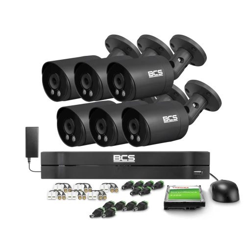 Na zdjęciu znajduje się zestaw do monitoringu składający się z sześciu czarnych kamer BCS, rejestratora oraz akcesoriów takich jak kable i zasilacze. W tle widoczny jest dysk twardy marki Toshiba.
