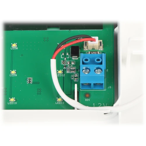 Zdjęcie przedstawia płytkę drukowaną z niebieskim złączem śrubowym oraz podłączonymi do niego przewodami. Na płytce widoczne są również diody LED i inne elementy elektroniczne.